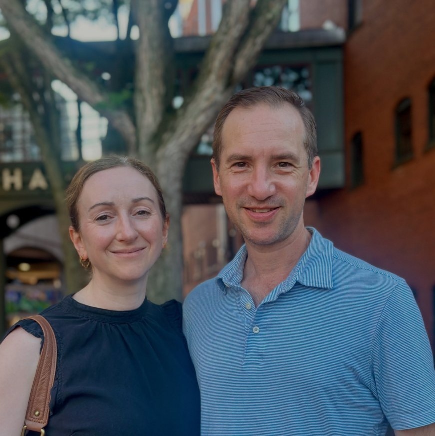 Chris and his wife Kate smiling together outside a brick building
